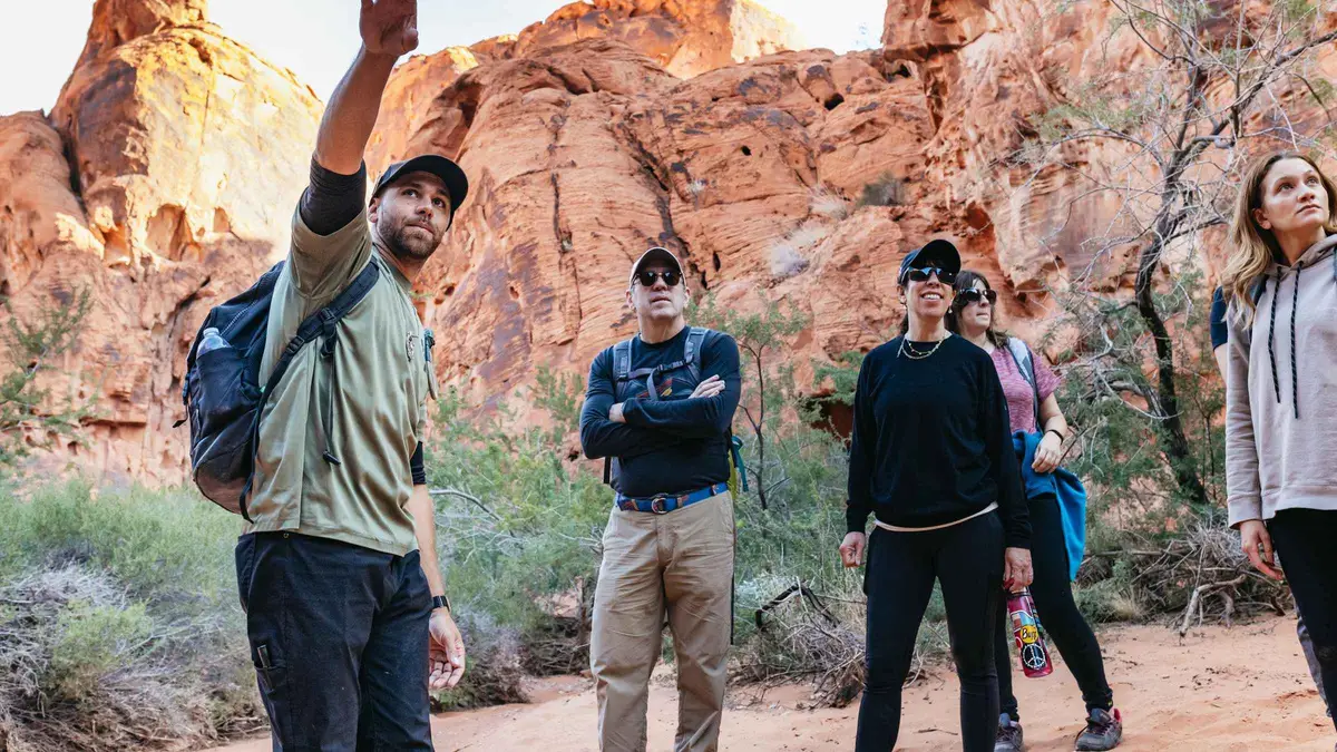 Hikers scrambling across red sandstone on a guided hike in Valley of Fire State Park on a tour from Las Vegas, Nevada